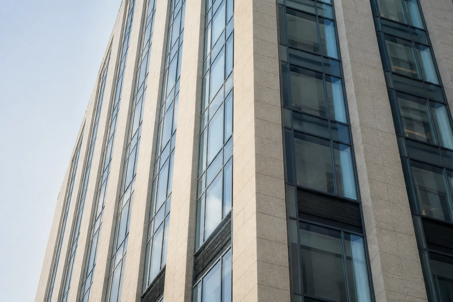Architektonischer Teilausschnitt eines Hochhauses mit Glas- und Steinfassade